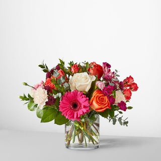Colorful rose and gerbera daisy bouquet featuring shades of pink, coral, white, and red — elegant glass vase arrangement for birthdays and celebrations in Toronto