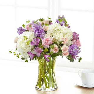 Delicate floral bouquet in vase with white hydrangea, pink spray roses, and lavender stock for home or gift