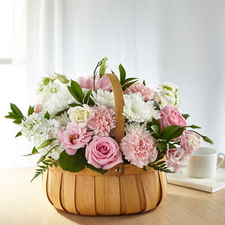 Send soft pink sympathy flowers with roses, carnations, and mums in a basket. Thoughtful funeral or home delivery available in Toronto.