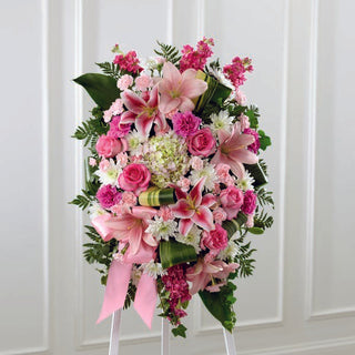 Elegant funeral standing spray with pink lilies, roses, and greenery for sympathy and condolences