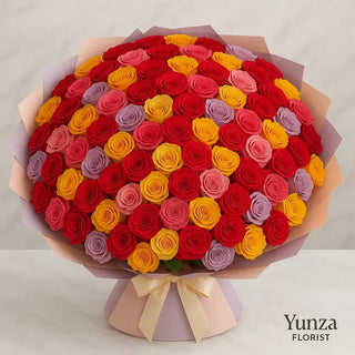 Grand 100 mixed roses arrangement with red, yellow, pink, and lavender blooms, wrapped in deluxe pastel paper and tied with an elegant satin ribbon — large luxury bouquet designed by Yunza Florist for Toronto flower delivery