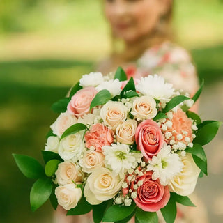 Romantic hand-tied bridal bouquet featuring peach roses, white roses, and chrysanthemums