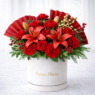 Elegant Lunar New Year floral arrangement featuring red roses, lilies, and greenery in a white hatbox by Yunza Florist