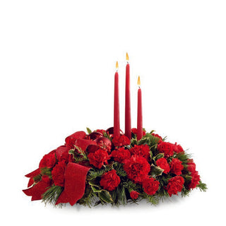 Red rose and carnation arrangement with greenery and red taper candles — perfect for holiday dinners