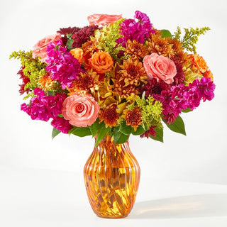 Elegant fall flower arrangement with coral roses, magenta stock, and orange chrysanthemums in an amber vase — Yunza Florist Toronto