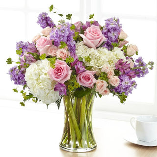 Fresh floral vase bouquet featuring white hydrangea, soft pink spray roses, and fragrant lavender stock