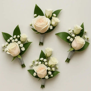 Elegant ivory rose boutonnieres wrapped in silver ribbon for groomsmen