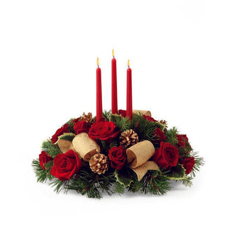 Luxury holiday floral arrangement with red roses, gold ribbon, and evergreen branches in a festive design