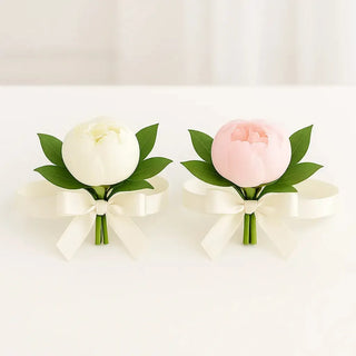 Elegant pair of peony wrist corsages with ivory ribbons, designed for the mother of the bride and mother of the groom. Pink and white peonies with greenery, handcrafted wedding flowers available in Toronto.
